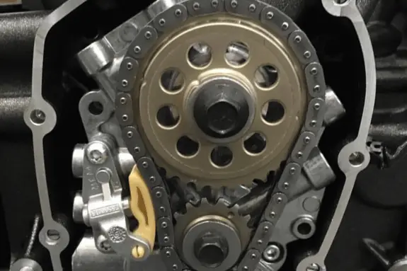 Harley cam chain tensioner exposed from an open engine casing. This is used to illustrate a common failure point on both twin cam engines, and milwaukee 8 engines like the Harley 114.