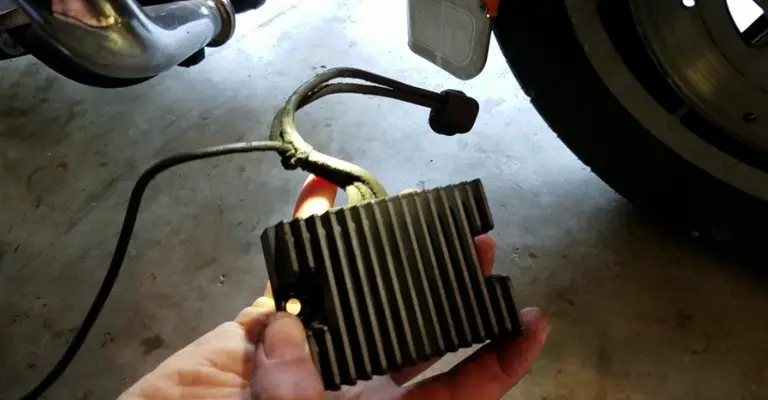 holding a harley davidson voltage regulator after it was removed from the bike