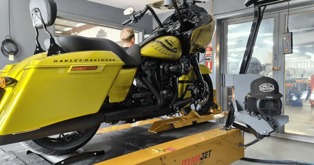 A yellow Harley Davidson motorcycle on a dynojet dyno in a Harley dealer's service department