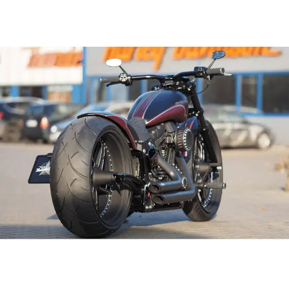A custom Harley Davidson in front of a dealership with a wide Metzeler ME888 installed on the rear wheel