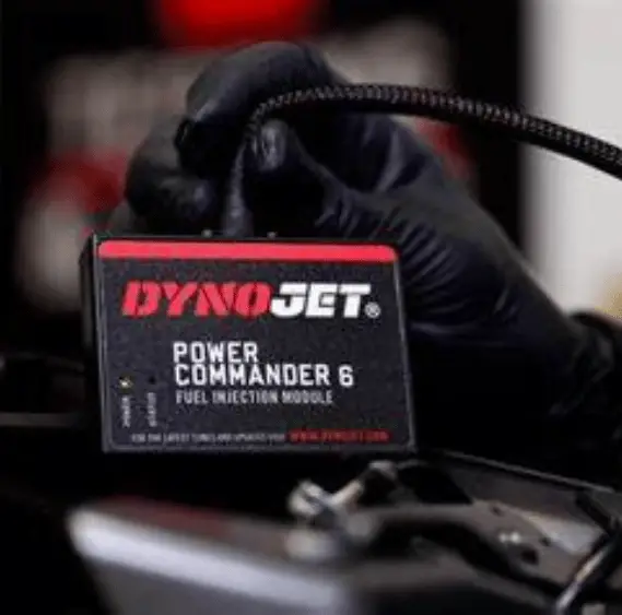 Dynojet Power Commander 6 that is installed on a bike, with a gloved hand in the background